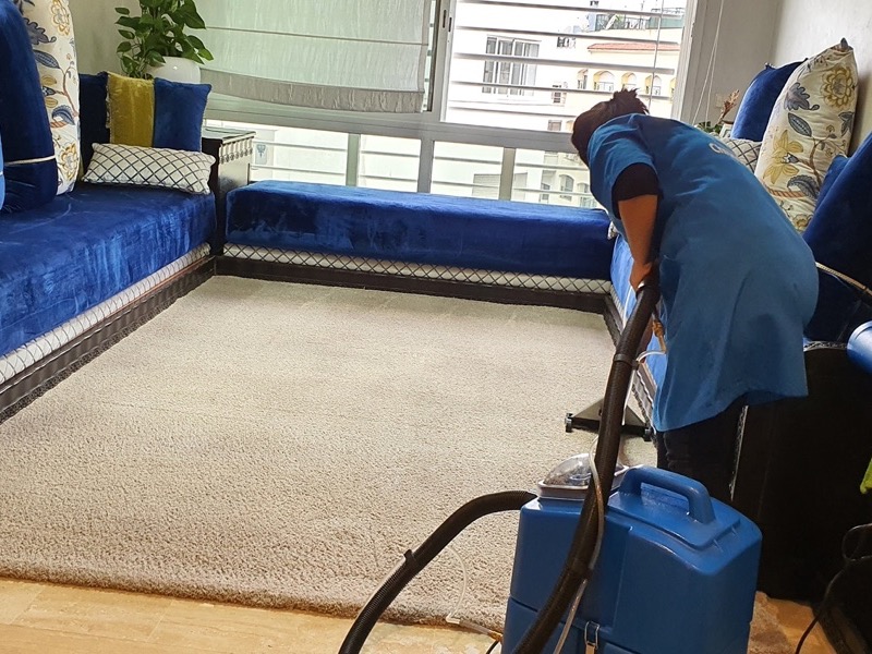 Intervenante Chronomenage nettoyant un tapis de salon marocain avec une machine d'injection-extraction
